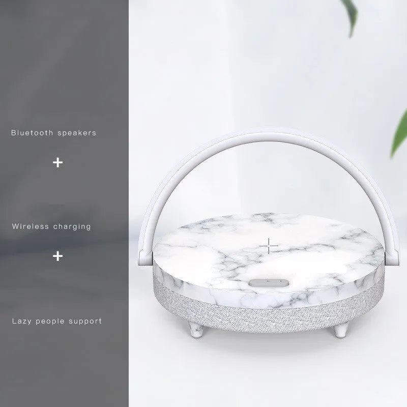 Wireless charging LED night light with Bluetooth speaker in marble pattern finish on a wooden table.