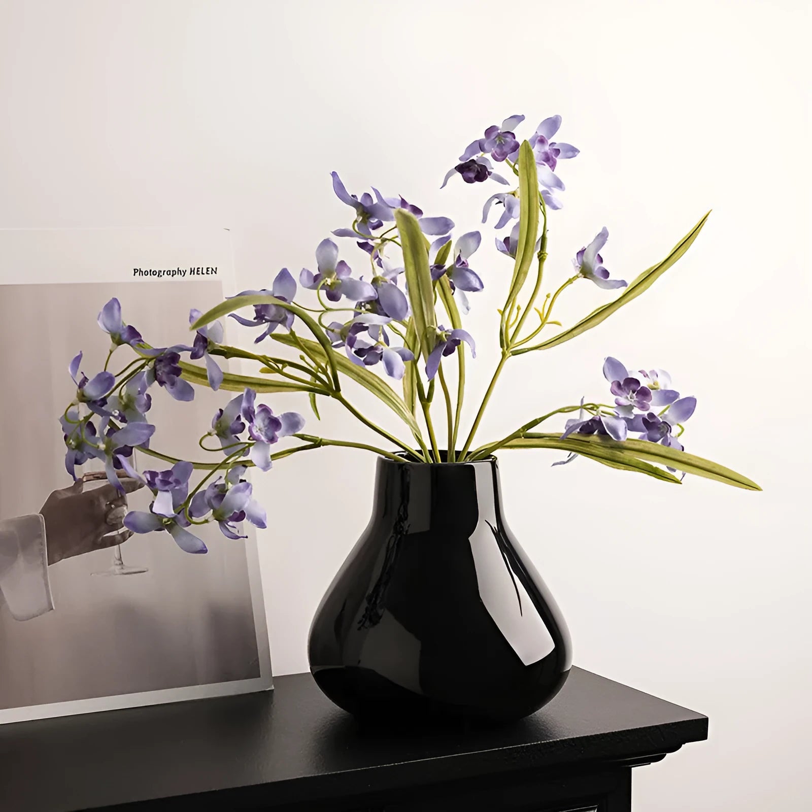 Ceramic round belly vase with coloured glaze finish in black or white, shown with artificial orchid stems