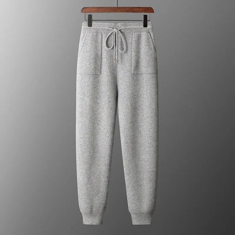 Man wearing a light grey hooded cashmere sweatshirt and matching long pants from a winter leisure set.