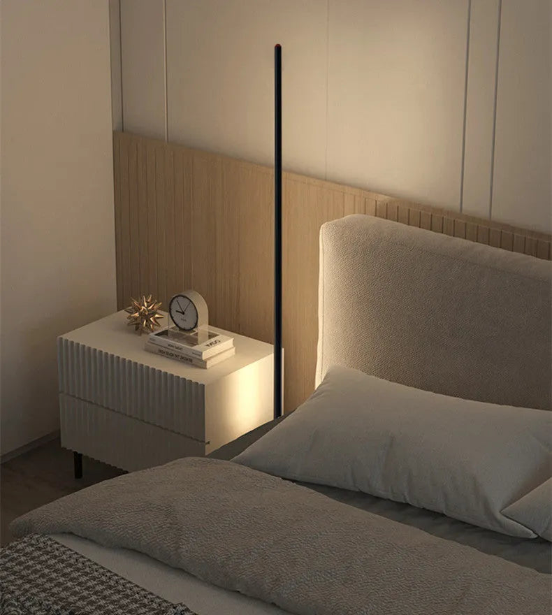 Vertical aluminium alloy floor lamp with a simple modern design, shown in a living room setting.