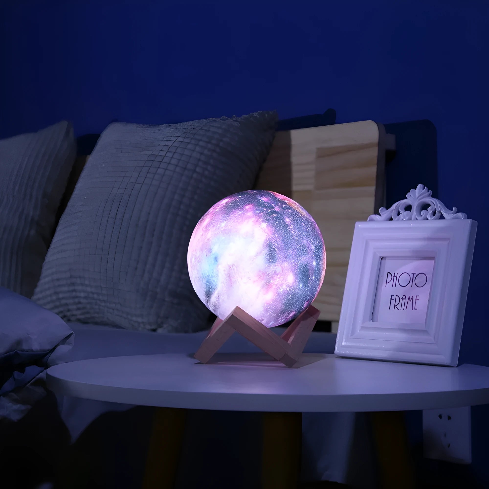 3D printed spherical lunar night light glowing with soft colour-changing LED light on a dark surface.