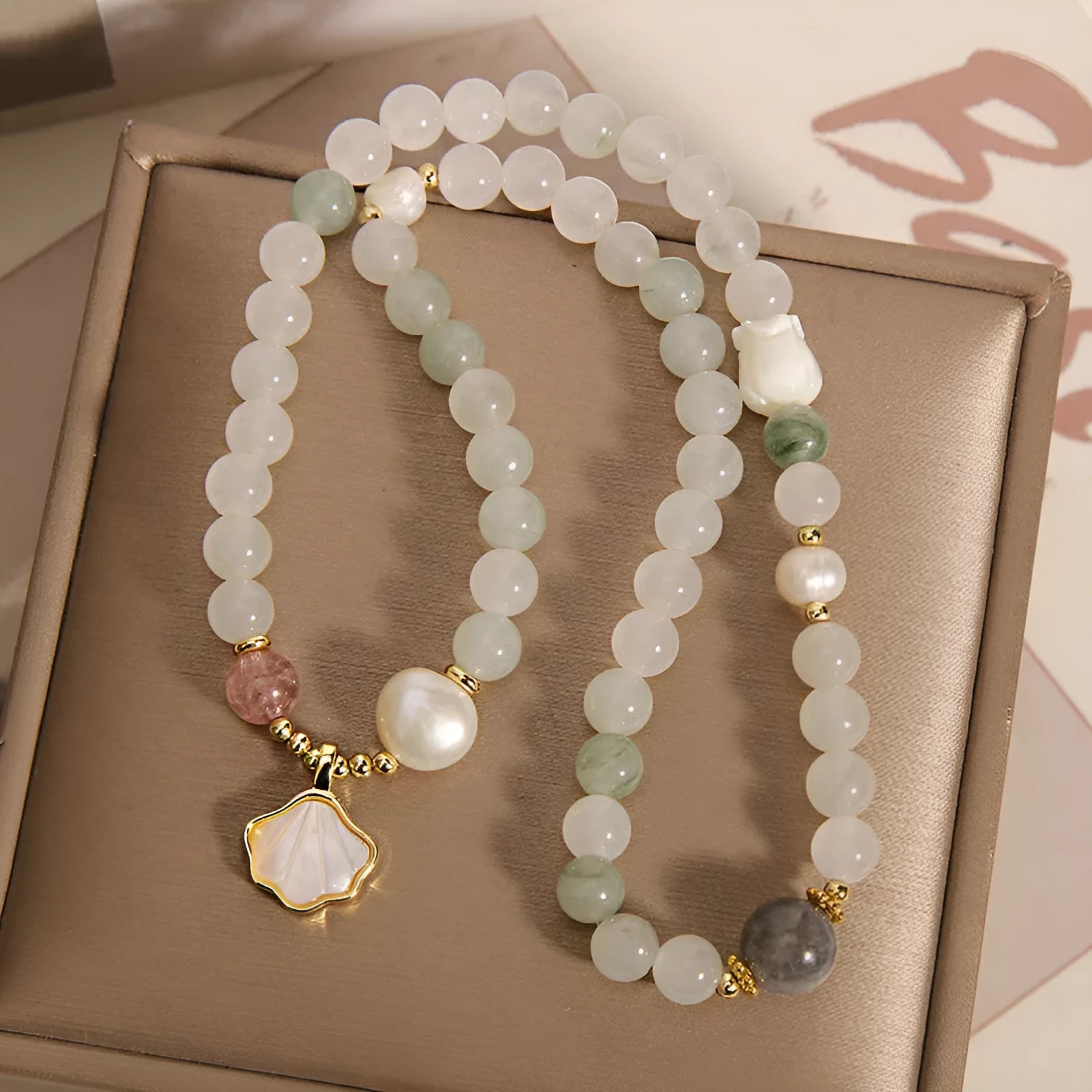 Women's crystal bracelet with a carved jade shell ginkgo leaf pendant on a gold-plated setting.