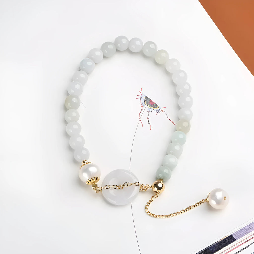 Close-up of a green jade and pearl bracelet with a geometric peace buckle on an elastic band.