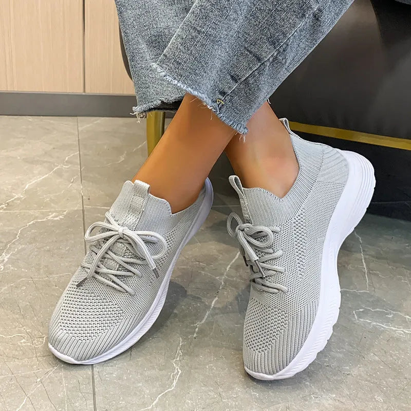 Women's low-top running shoes in Flyknit mesh, shown in creamy white colour with flat rubber sole.