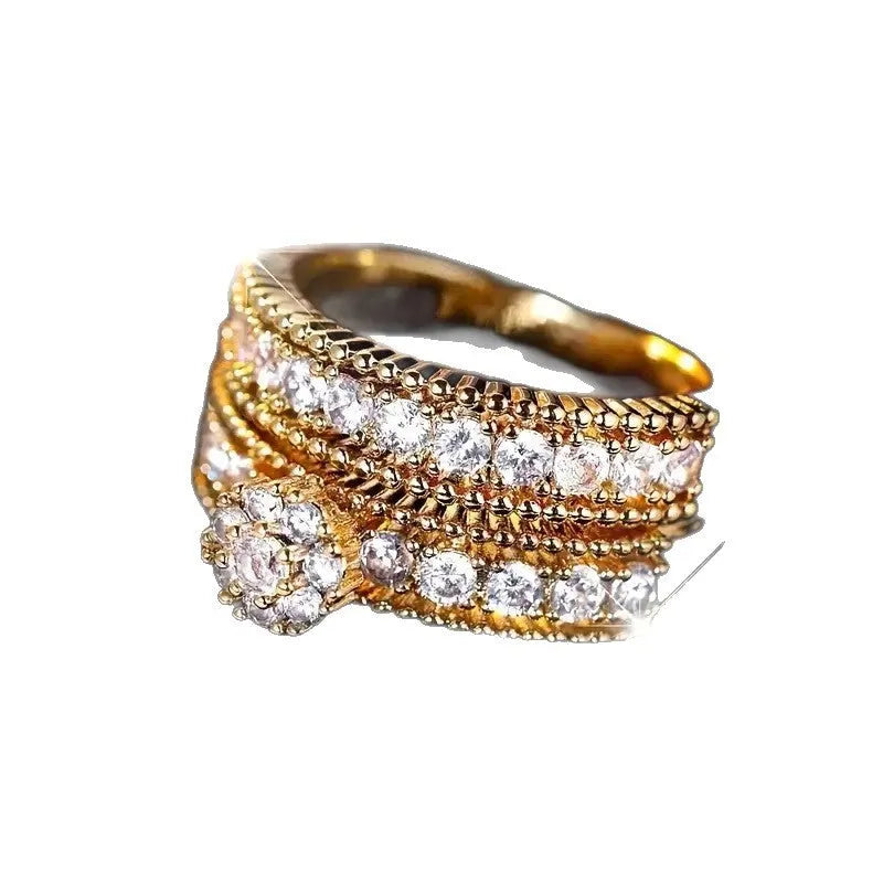 Two geometric gold electroplated zinc alloy rings on a flat surface