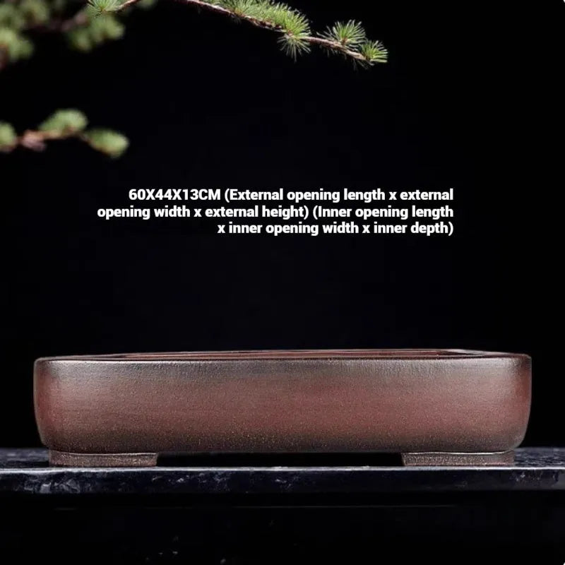 Large handmade antique rectangular purple clay flower pot on a table.