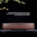 Large handmade antique rectangular purple clay flower pot on a table.