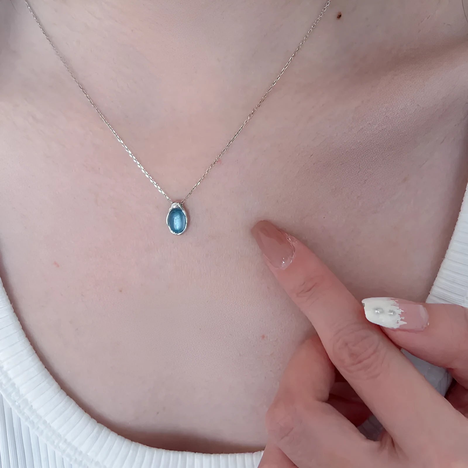 Geometric navy blue and platinum colour water drop pendant necklace on a cross chain.