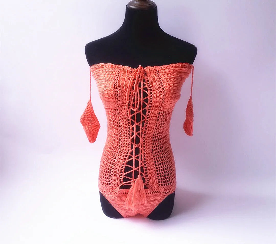 A woman's off-shoulder one-piece swimsuit on a hanger, shown in a light pink colour.