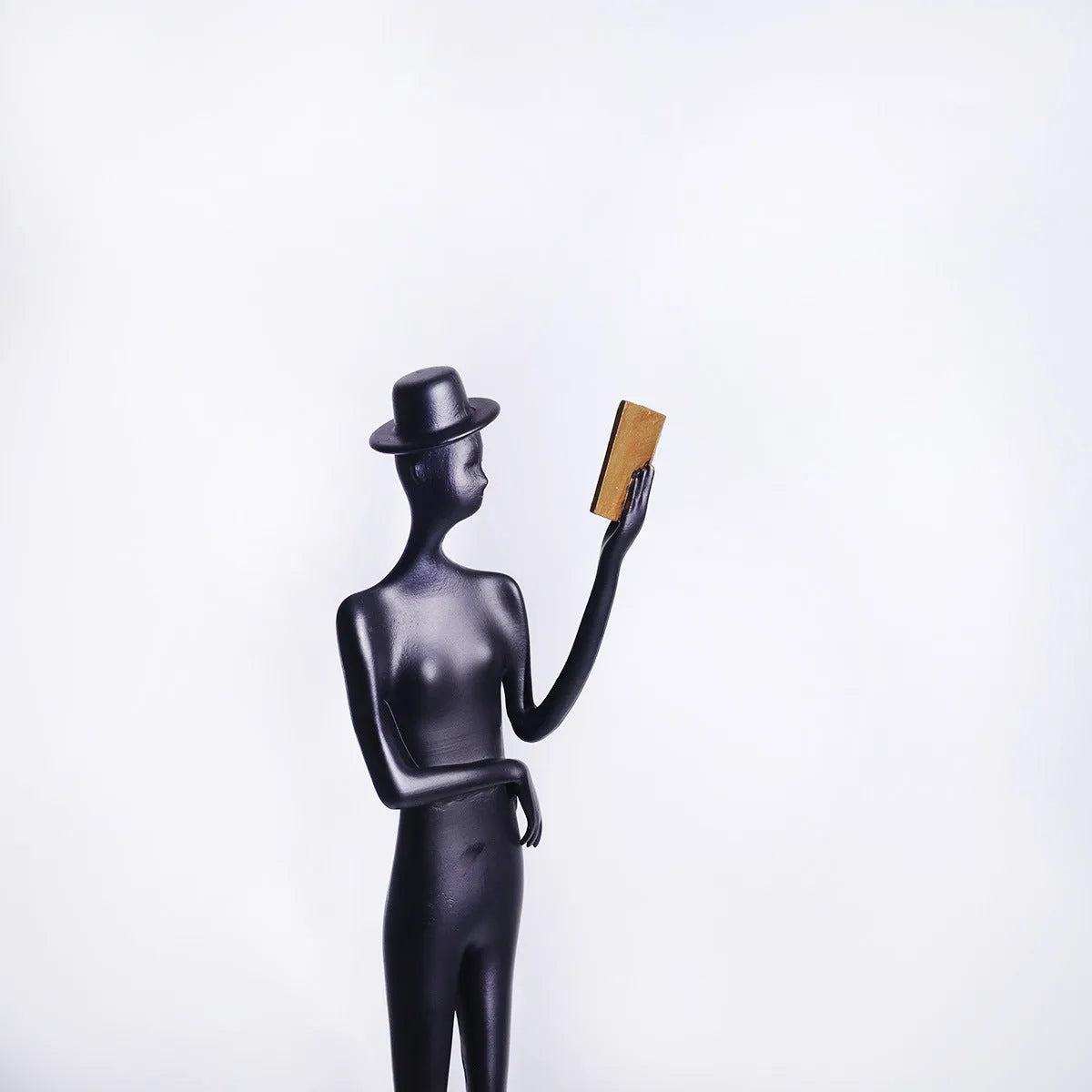 Black aluminium reading woman desk sculpture measuring 12cm by 12cm by 51cm