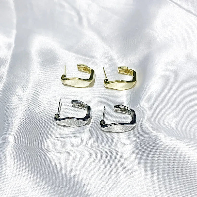 Irregular C-shaped metal stud earrings in Gold finish, minimalist design for everyday wear.