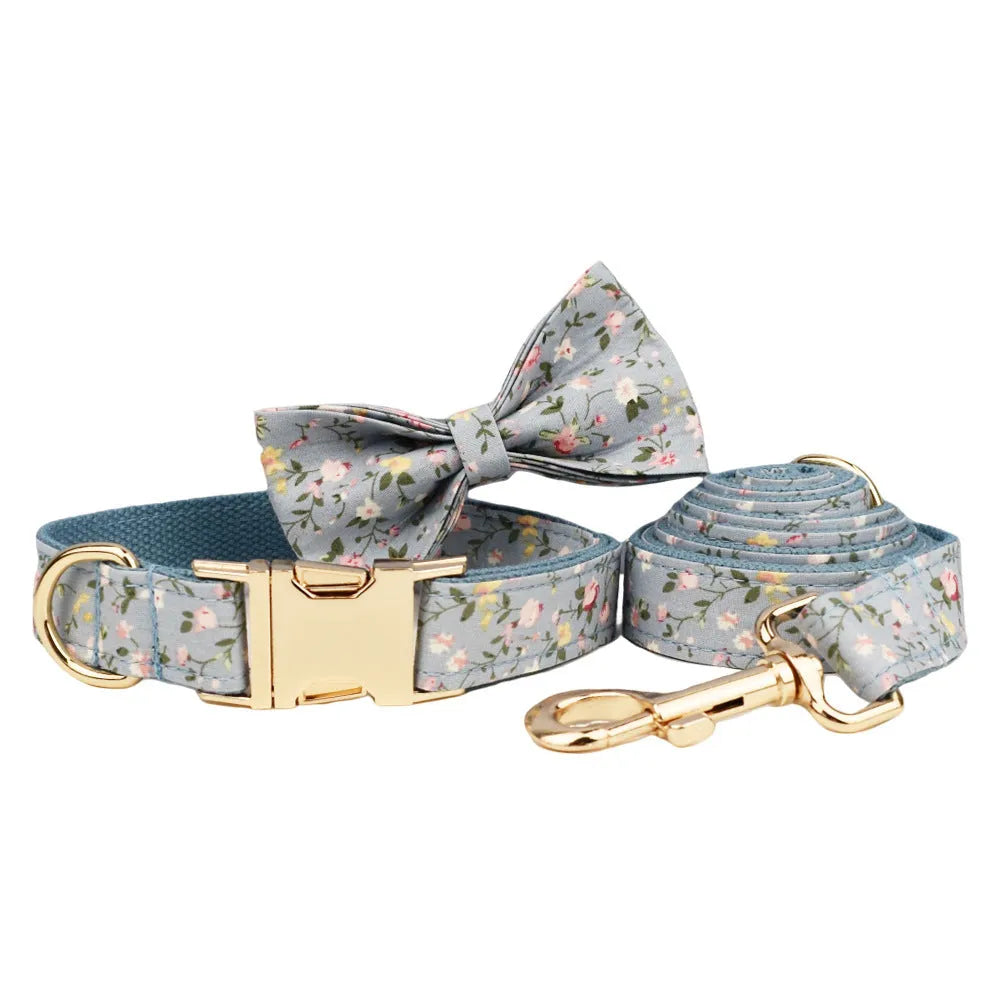 Blue floral patterned dog collar and matching leash, vest, and bow set on a white background.