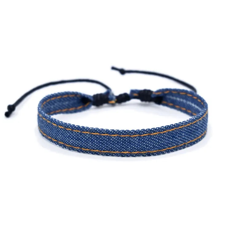 Handmade denim fabric bracelet carrying strap in national style on wrist, showing charm attachment point.