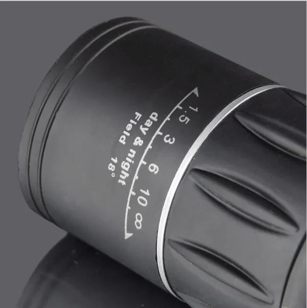 Black 16x52 monocular telescope showing eyepiece and objective lens, placed on a surface.