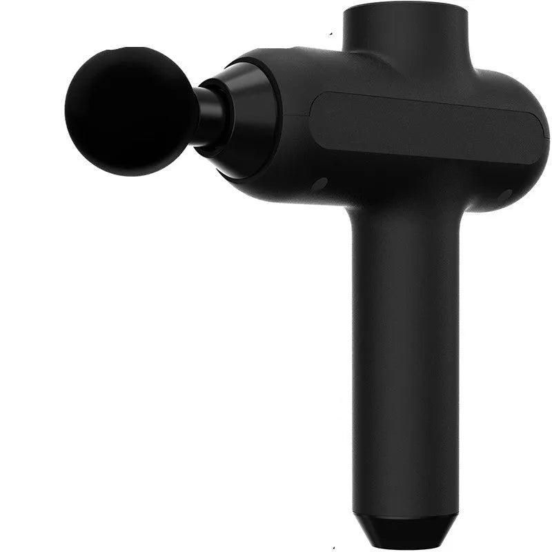Handheld black electric muscle massager with six different massage heads on a table.