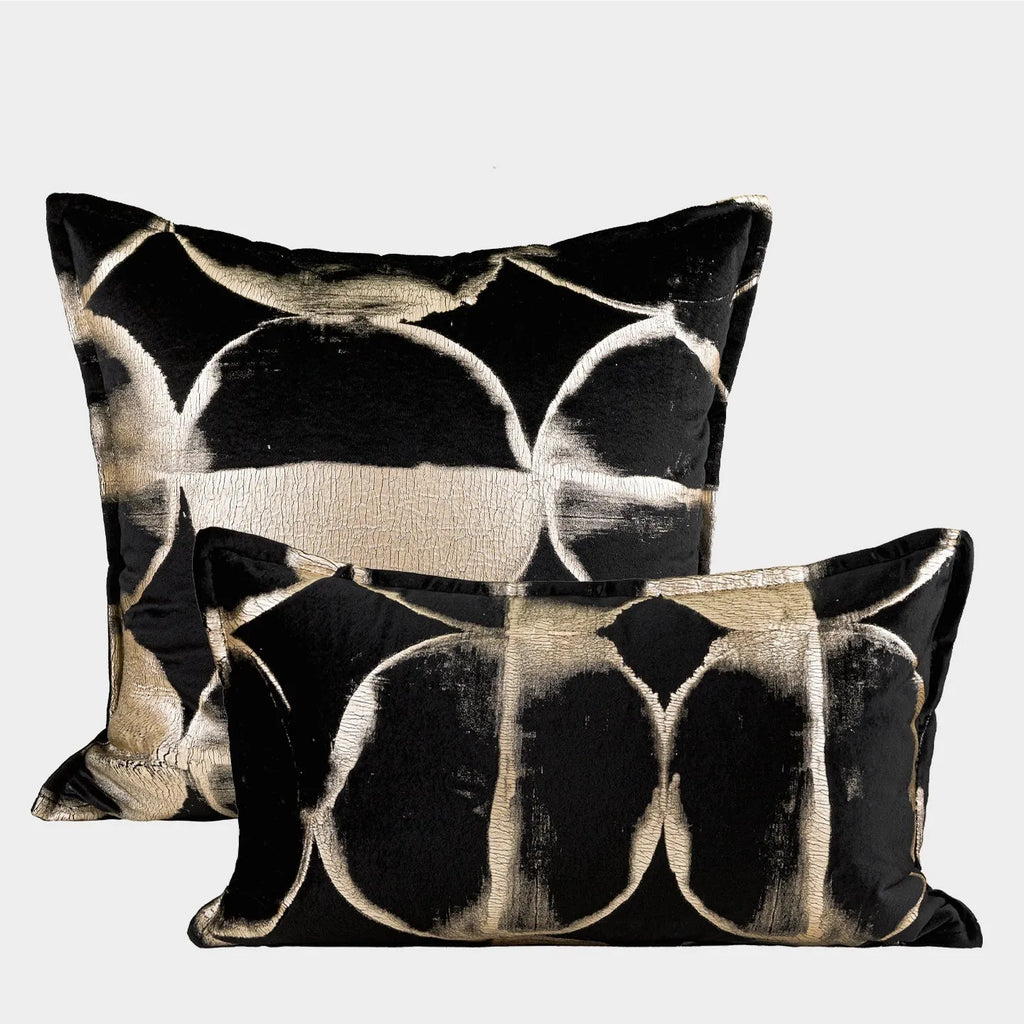 Black and gold abstract print flannel decorative cushion pillow on a sofa.