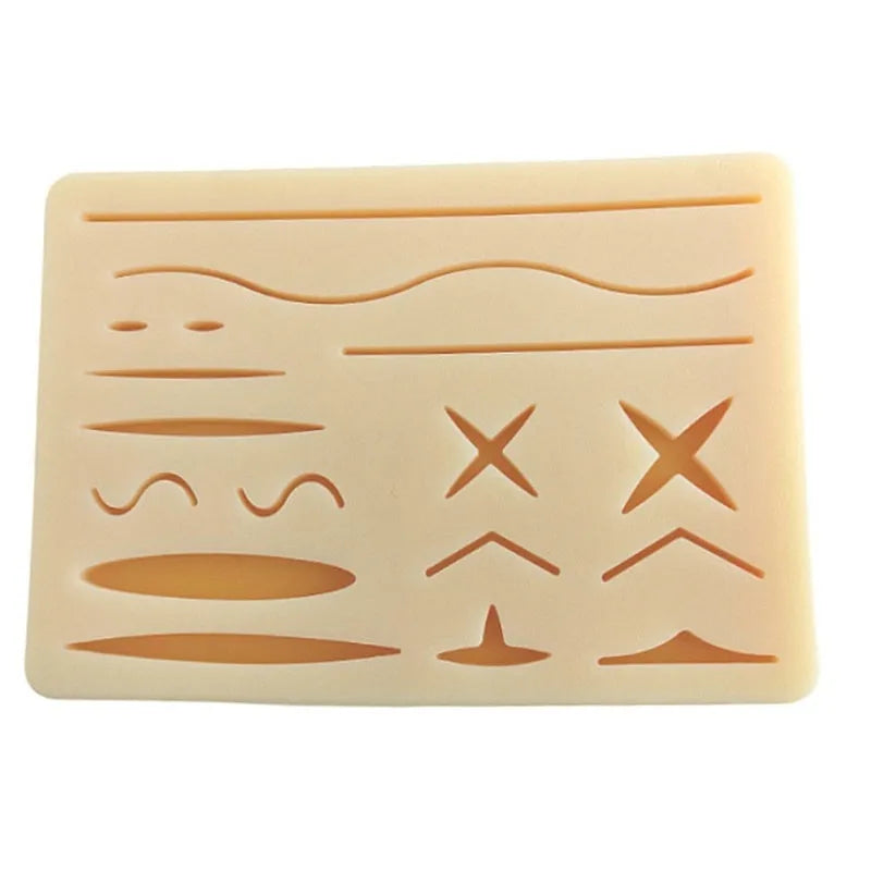 Medical student training kit with black silicone suture pad, tools, and multi-wound block on a table