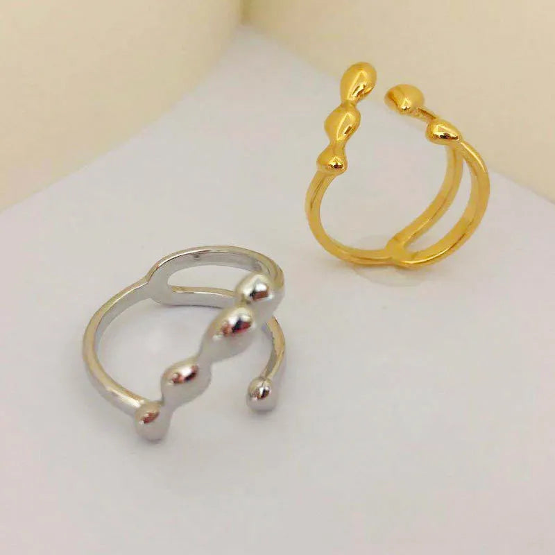 Open circle brass fashion ring with spherical beads in gold tone on a hand.