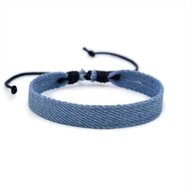 Handmade denim fabric bracelet carrying strap in national style on wrist, showing charm attachment point.