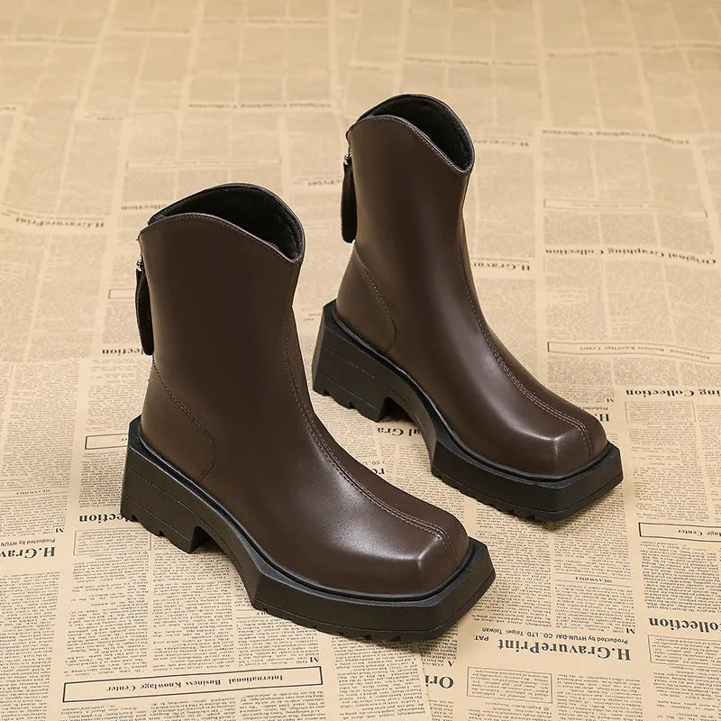 Black women's platform Martin boots with a square toe and back zipper on a wooden floor.