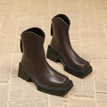 Black women's platform Martin boots with a square toe and back zipper on a wooden floor.