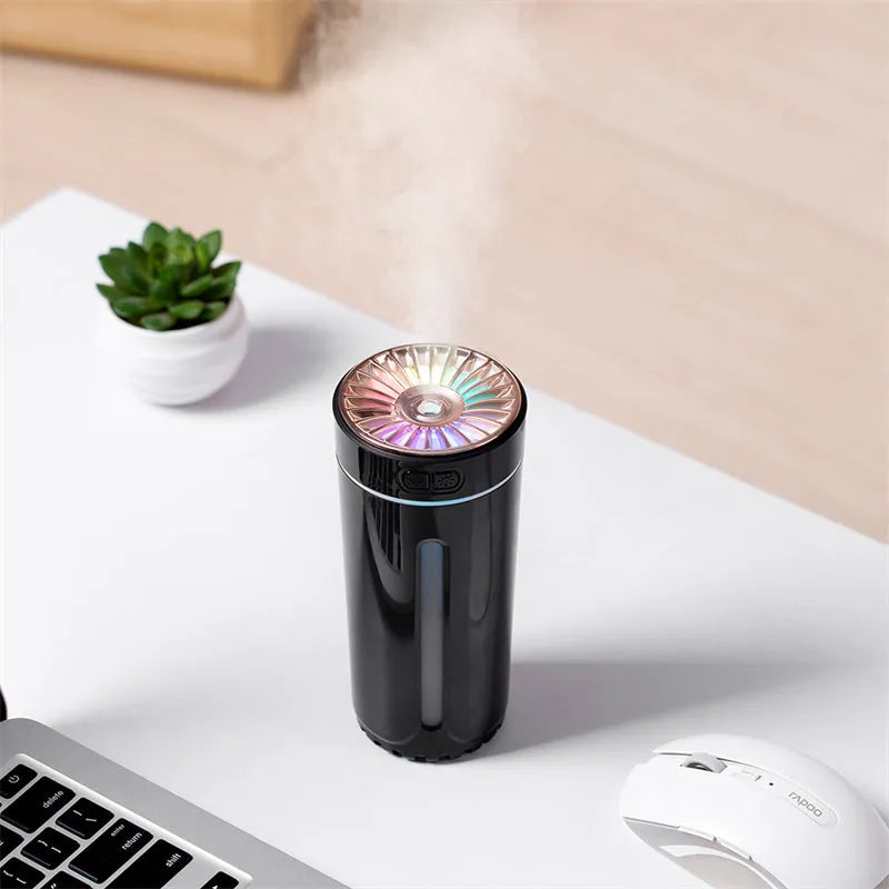 Black and white portable USB rechargeable humidifier with colourful LED lights on a car cup holder.