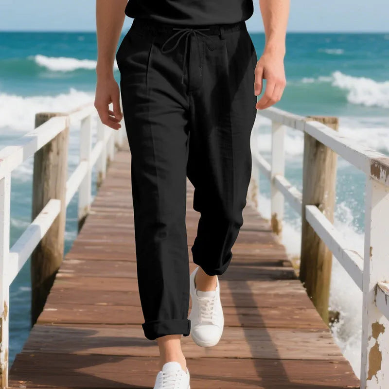 Man wearing light khaki linen casual trousers with a drawstring waist and straight leg.