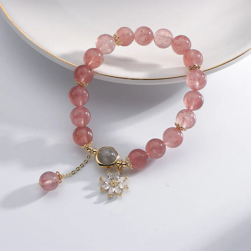 Mori style crystal bracelet with strawberry quartz stones and floral design details on a wrist.