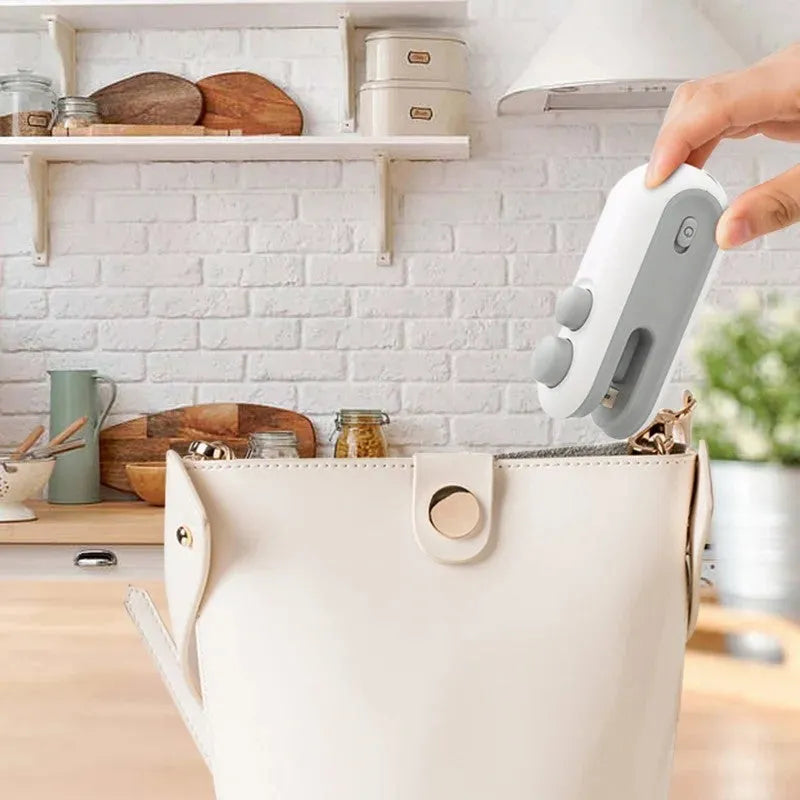 White and blue handheld USB rechargeable bag heat sealer with built-in cutter on a kitchen counter