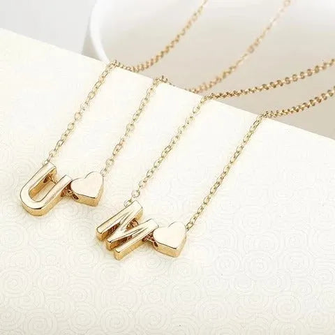 Gold alloy peach heart pendant necklace with a letter detail on a delicate chain.