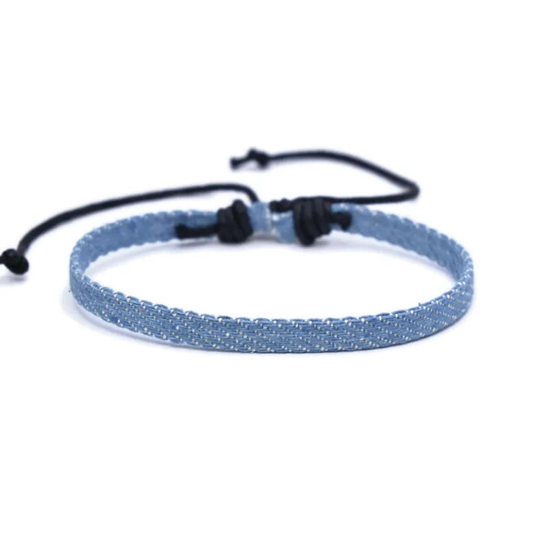 Handmade denim fabric bracelet carrying strap in national style on wrist, showing charm attachment point.