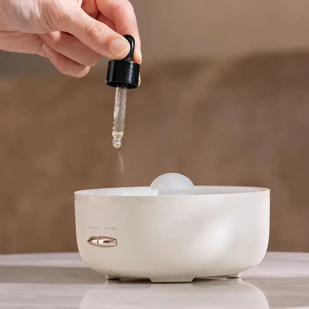 Round resin aroma diffuser with colourful light in beige, on a desktop, with a single fog nozzle