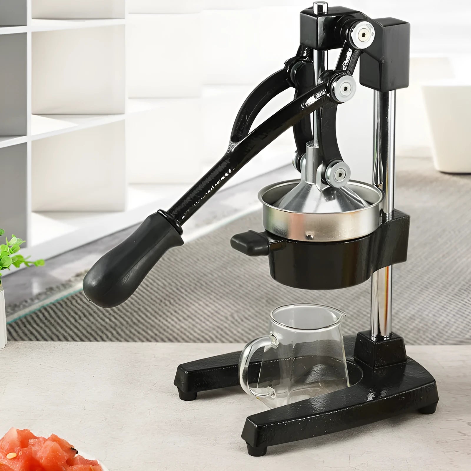 Black and white manual cast iron juice press with stainless steel funnel, 40cm tall.