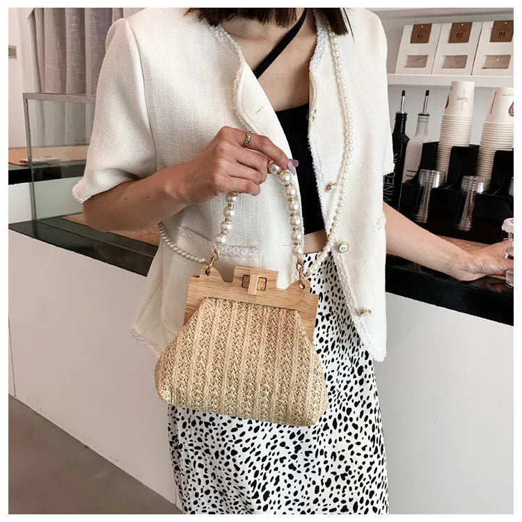 Women's straw woven shoulder bag with pearl chain detail showing interior organisation compartments