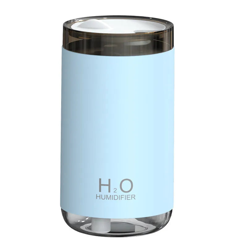 White jellyfish-shaped USB humidifier emitting smoke ring mist with warm night light glow on a table.