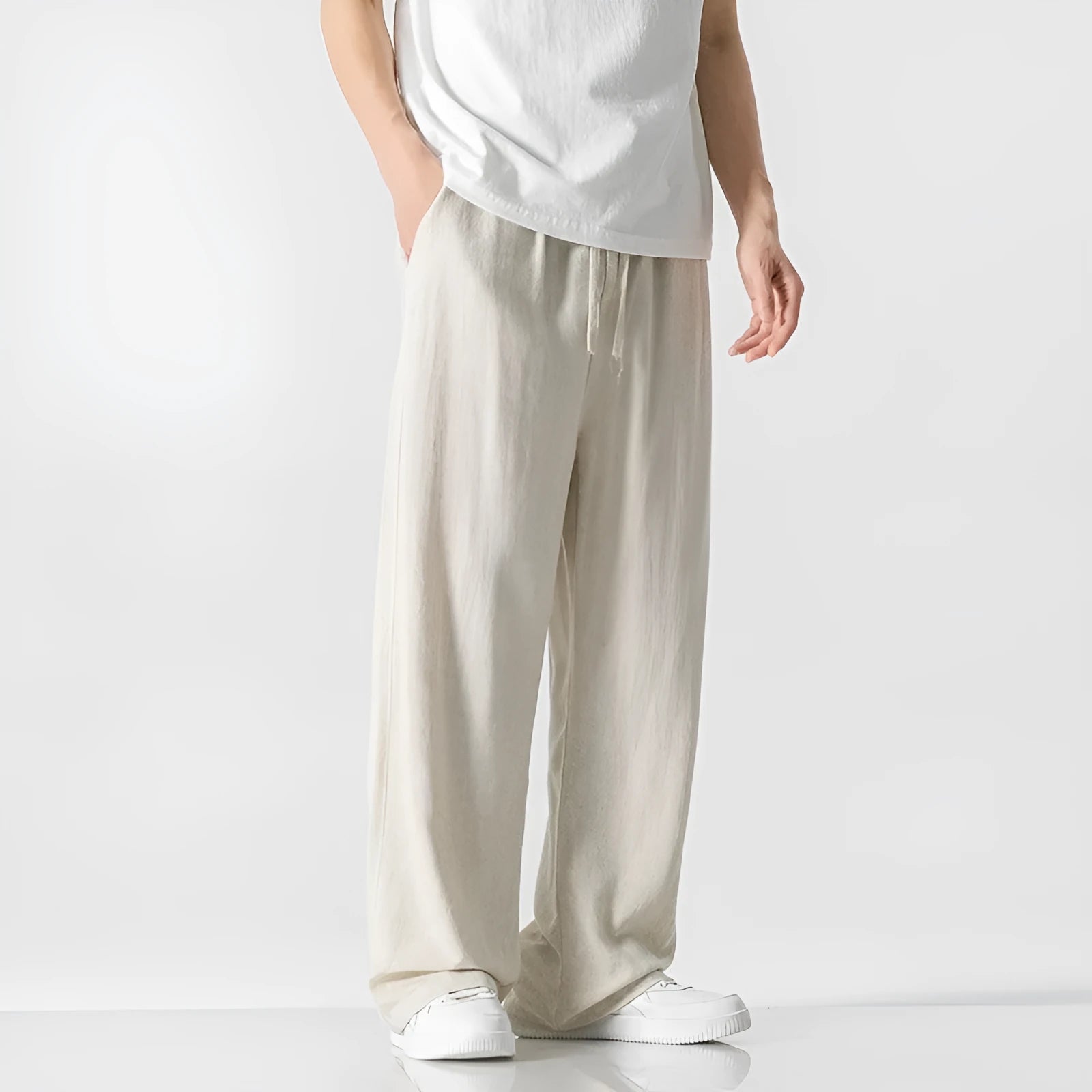 Man modelling beige linen drawstring trousers with a straight-leg cropped fit.