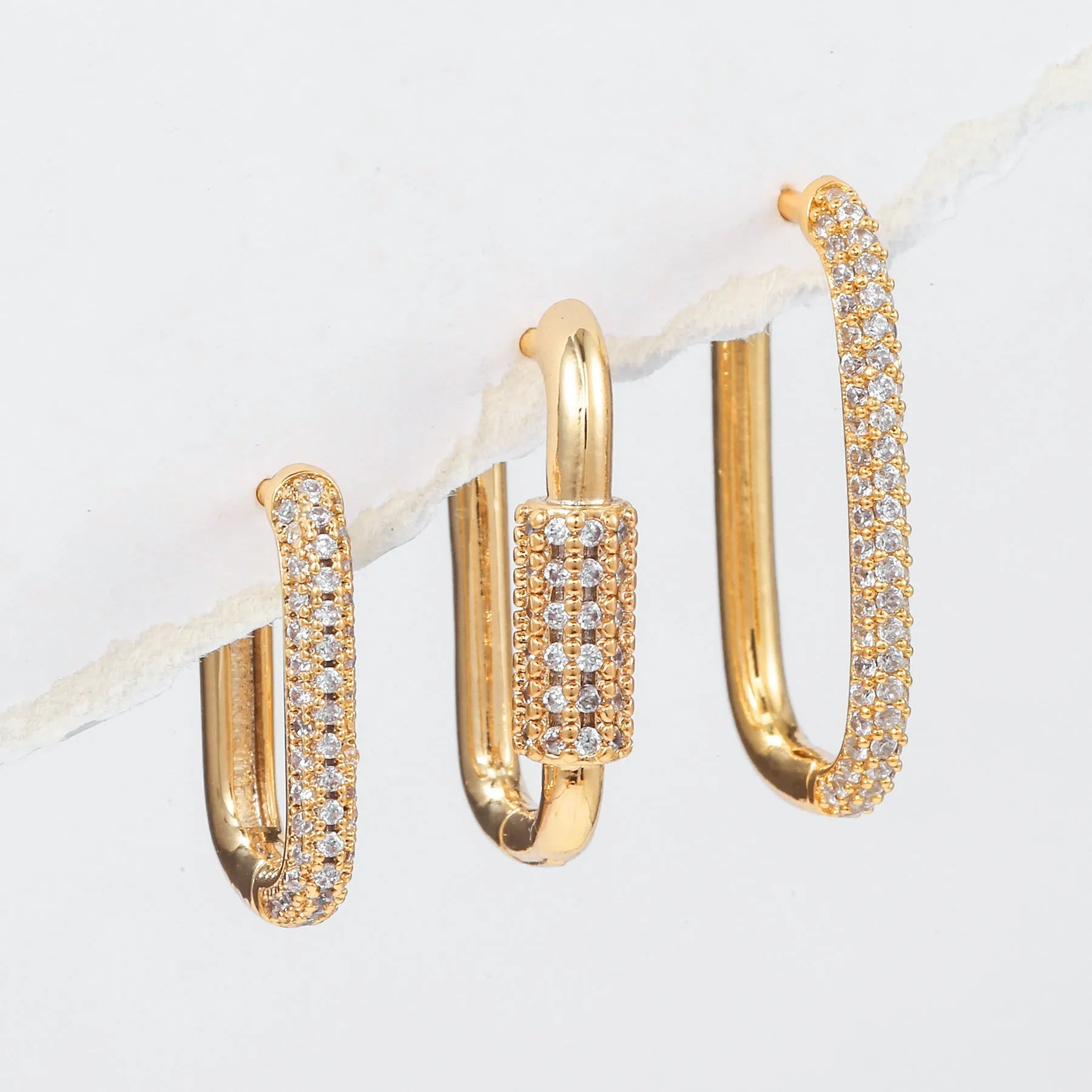 Three geometric ear clips with micro-inlaid zircon stones on copper, showing gold and white gold colour options