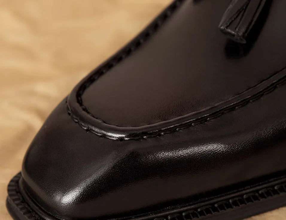 Men's black genuine leather slip-on loafers showing polished finish and rubber sole