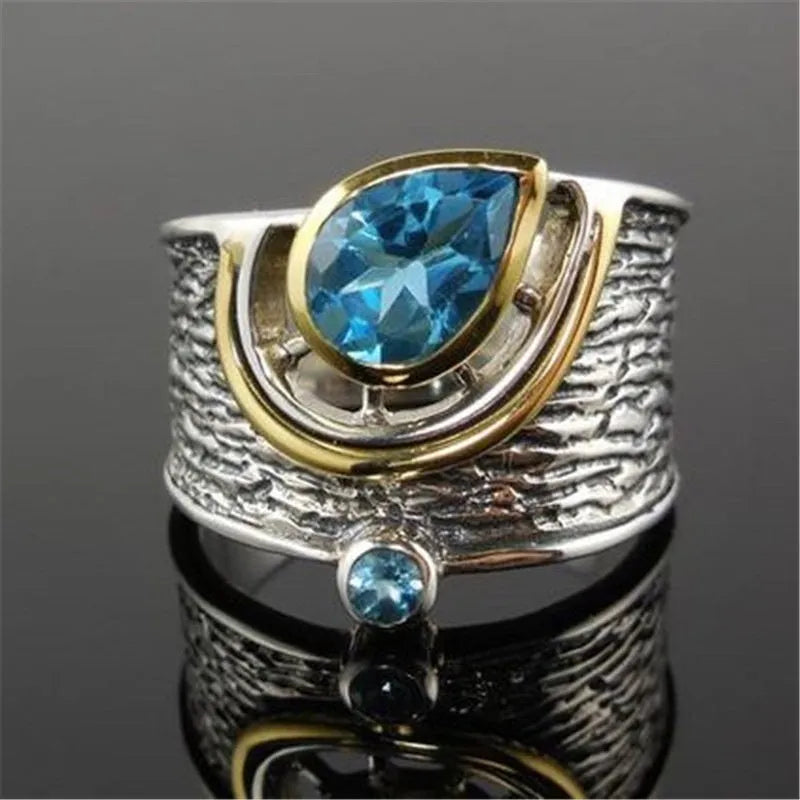 Close-up of a women's blue zircon alloy ring with a drop shape and Chinese-inspired design on a hand.