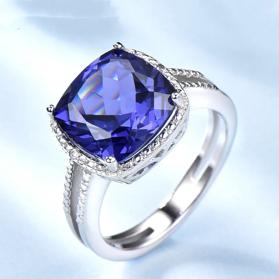 Blue Tanzanite stone set in a sterling silver 925 ring for women, shown on a finger.
