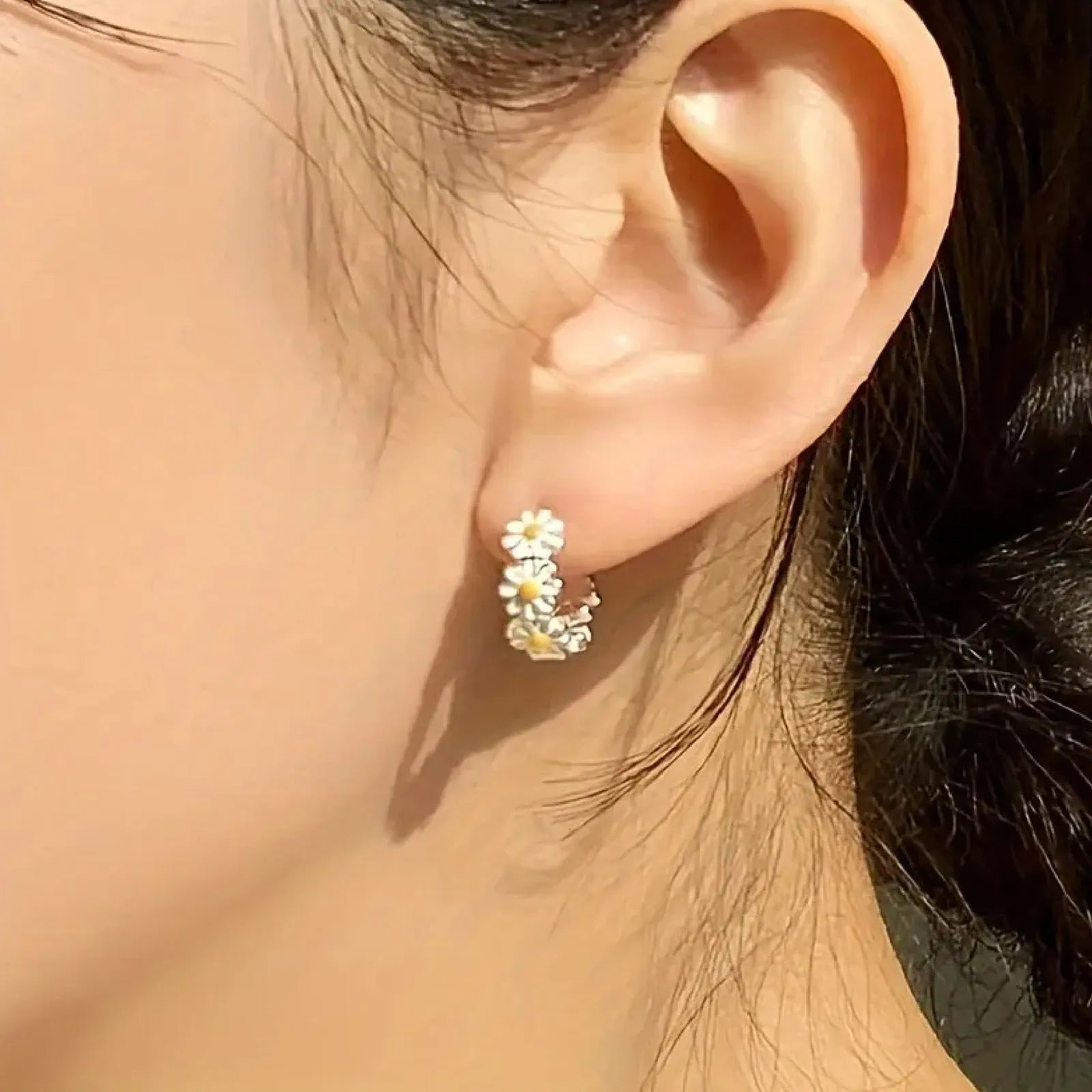 White daisy flower fashion ring earrings with platinum-set gems on a model.