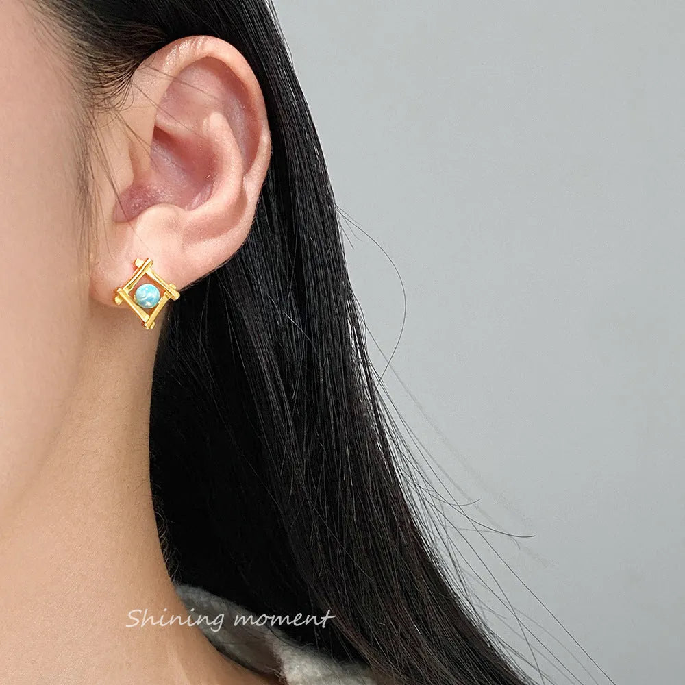 Geometric cross-shaped silver stud earrings for women on a white background.