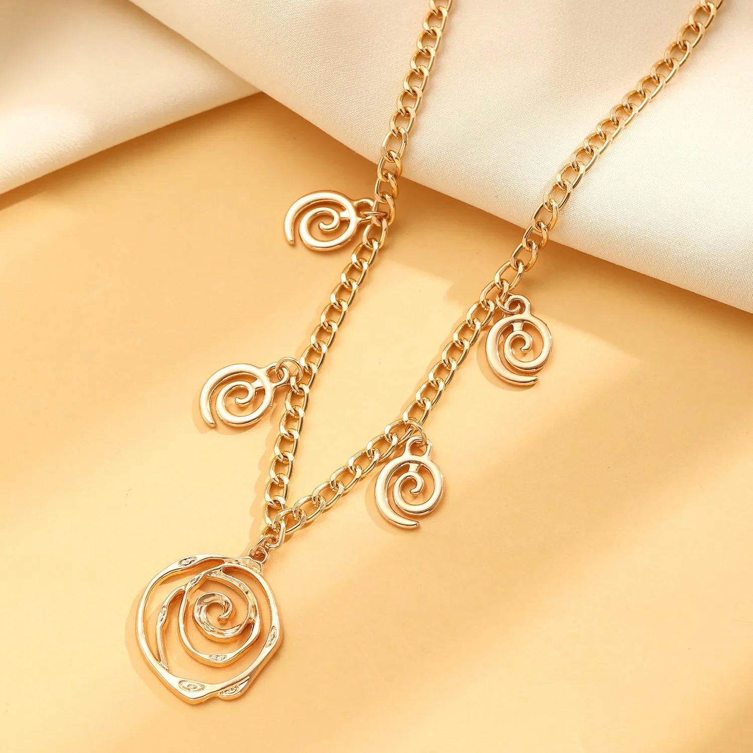 Women's spiral donut jewellery set showing necklace, bracelet and earrings in gold alloy finish