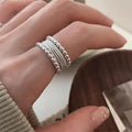 Close-up of a copper ring with a woven twisted geometric multilayer design on a model's hand.