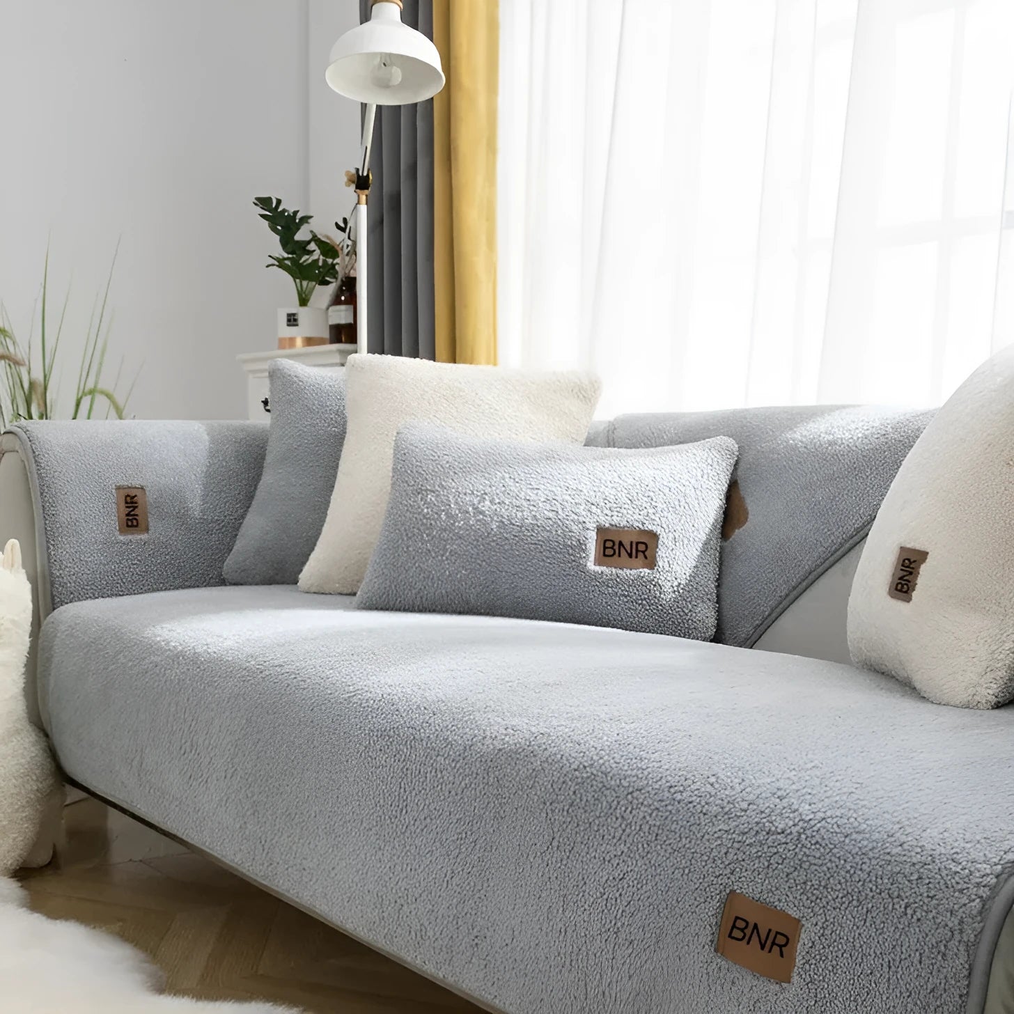 Lambswool-style solid colour sofa cover and pillow on a grey sofa.