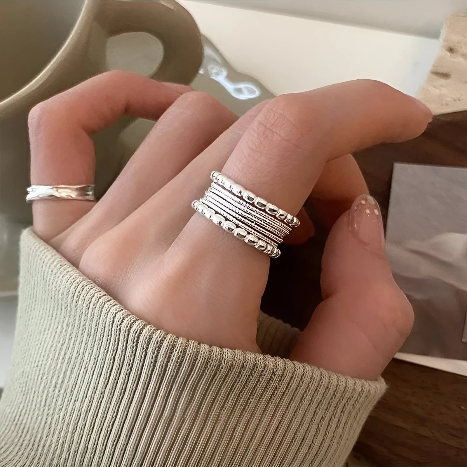 Close-up of a copper ring with a woven twisted geometric multilayer design on a model's hand.