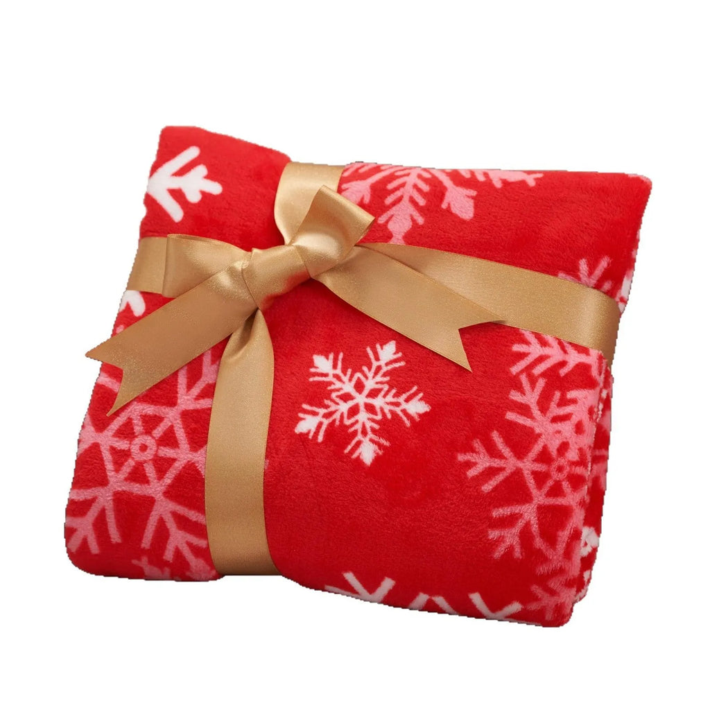 Soft red polyester flannel Christmas blanket with festive pattern draped over a bed