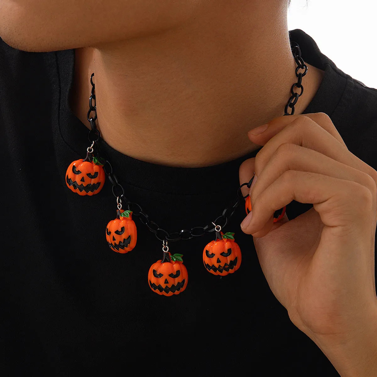 Halloween necklace showing a cartoon ghost and pumpkin acrylic pendant on a metal chain, in mixed colours.