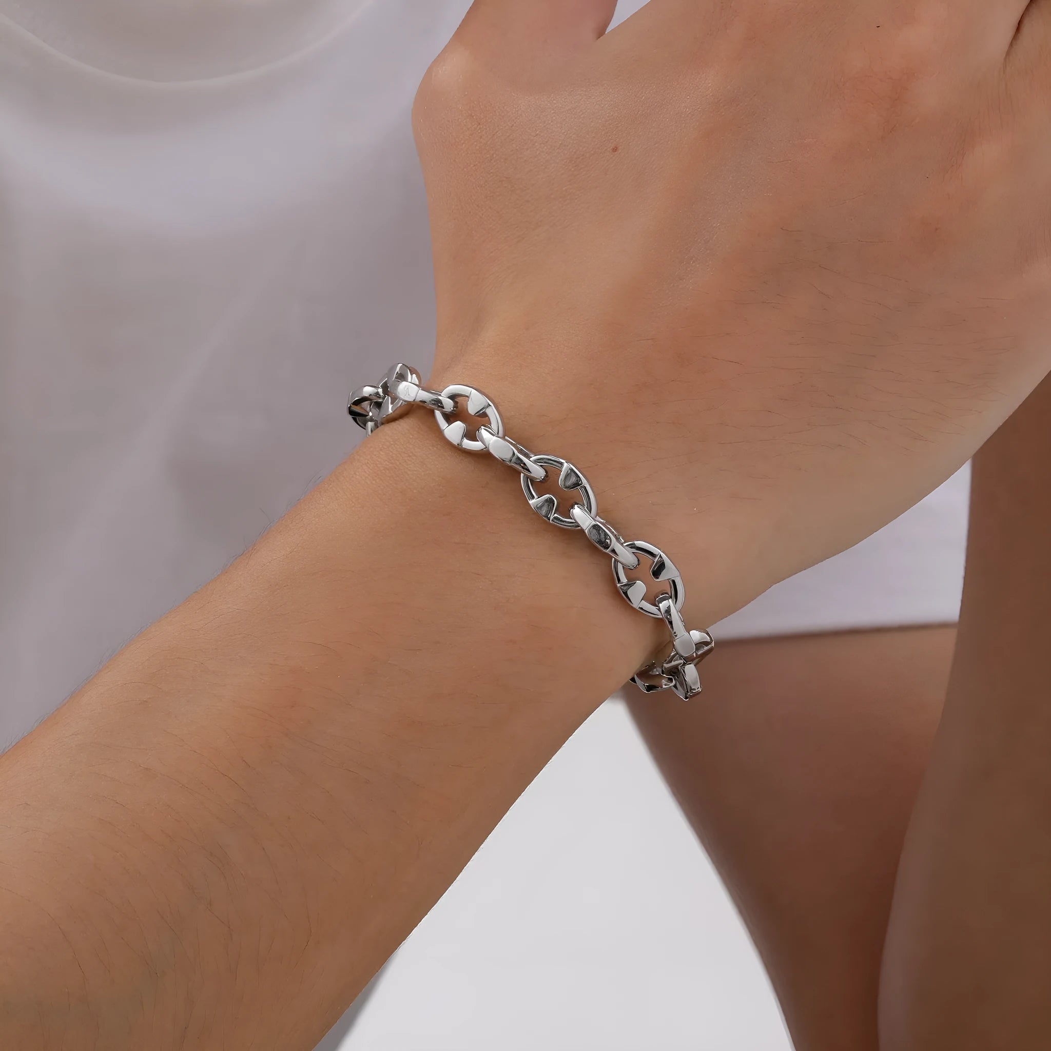 A thick geometric chain bracelet made from stainless steel in a steel colour, shown on a wrist.