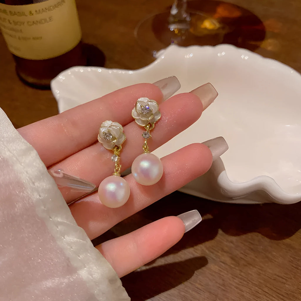 A pair of camellia flower design stud earrings for women in a pearl-white alloy.